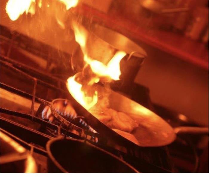 Fire engulfed frying pan in commercial kitchen